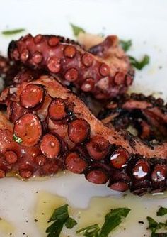 an octopus is sitting on top of some broccoli florets and garnished with parsley