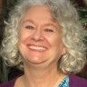 an older woman with white hair smiling at the camera