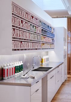 a white kitchen with lots of bottles on the wall above the sink and counter top