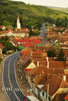 an aerial view of a small town with lots of houses on the sides and a steep hill in the background