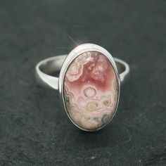 "This ring is made from beautiful genuine Rhodochrosite, and is size 9. Rhodochrosite is a beautiful natural pink stone with layers of soft and radiant pink, cream and soft taupe. The oval gemstone is 1/2\" x 3/4\" and is set in sterling silver. Your sterling silver ring will be shipped gift boxed with a descriptive jewelry card listing gemstones and materials used." Sterling Silver Ring With Large Pink Stone, Pink Oval Ring With Large Stone, Pink Oval Spiritual Ring, Pink Natural Stones Ring Jewelry, Oval Pink Ring With Large Stone, Unique Pink Rings With Large Stone, Pink Rings With Natural Stones For Gift, Pink Oval Cabochon Opal Ring, Pink Rhodochrosite