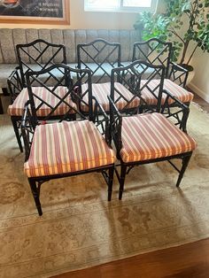 six chairs with striped cushions sit on the floor in front of a painting and potted plant