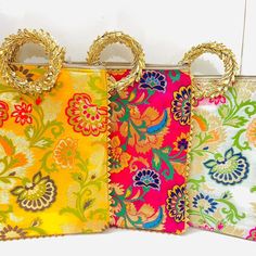 four purses are lined up in different colors and designs, each with gold handles