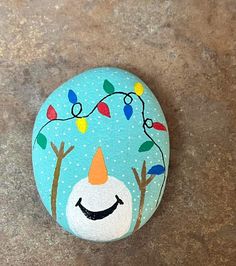 a painted rock with an image of a smiling snowman on it's face