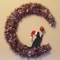 a christmas wreath with a cat in the center and a red ornament hanging from it