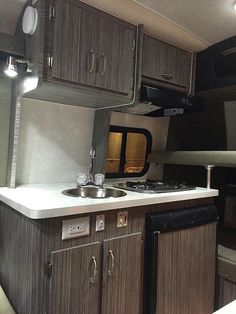 a kitchen area with sink, stove and oven in an rv or truck trailer that is parked