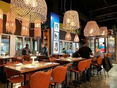 people sitting at tables in a restaurant with chandeliers hanging from the ceiling