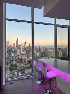 a bar with stools in front of large windows overlooking cityscape and skyscrapers