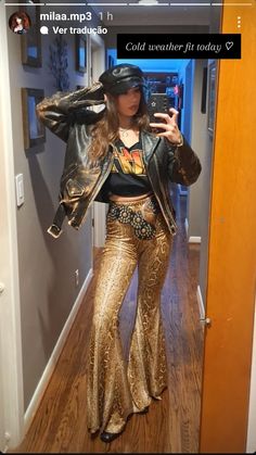 a woman taking a selfie in a mirror wearing gold pants and a leather jacket