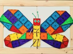 a colorful kite is hanging on a wooden frame in the shape of a dragonfly