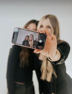 two women are taking a selfie with their cell phone in front of the camera