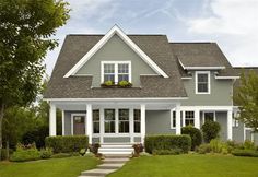 a gray house with white trim on the front and side windows is shown in this image