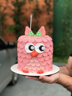 a person holding a pink cake decorated like an owl