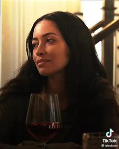 a woman sitting at a table with a glass of red wine in front of her