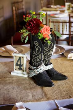 a cowboy boot with flowers in it sits on a table next to a number four sign