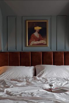 a bed with white sheets and pillows in front of a painting on the wall above it