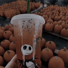 a person holding up a starbucks cup with jack skellings on it and pumpkins in the background