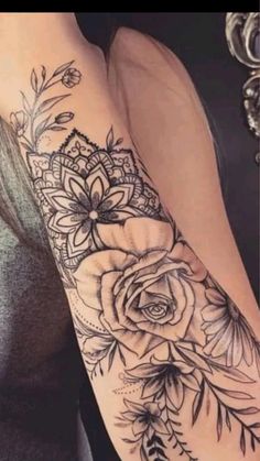 a woman's arm with flowers and leaves on it