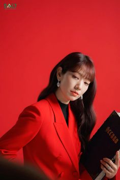 a woman in a red suit holding a book