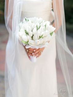 a bride holding a bouquet of white flowers