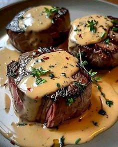 some steaks covered in sauce and garnished with parsley on a plate