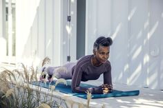 a woman is doing push ups on a yoga mat in front of a white building