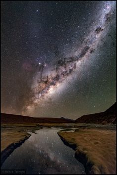 the milky shines brightly in the night sky above a body of water and mountains