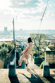 a woman walking up the side of a building on top of a wooden platform with power lines above her