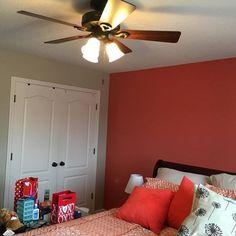 a bed room with a neatly made bed and a ceiling fan over it's headboard