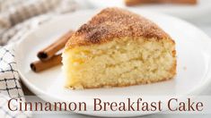 a slice of cinnamon breakfast cake on a white plate with cinnamon sticks in the background