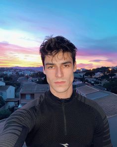 a man standing on top of a roof in front of a cityscape at sunset