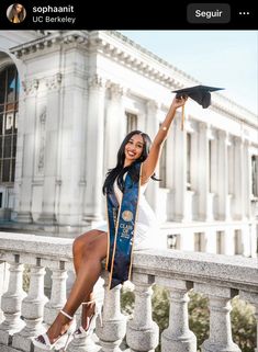 a woman is sitting on a balcony with her graduation cap in hand and she is smiling at the camera