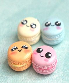 four macaroons with different designs on them are sitting next to each other and one is smiling