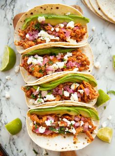 four tacos with meat, onions and cheese on them