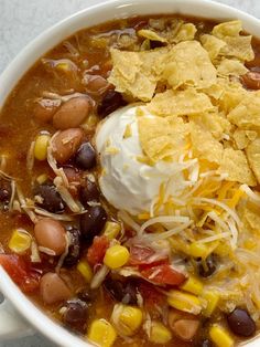 a white bowl filled with beans, corn and tortilla chips