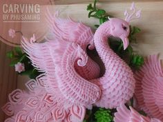 a pink sculpture of a bird on top of some green leaves and flowers with the words carving by phosaming above it