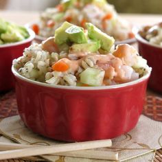 three red bowls filled with rice and vegetables on top of a table next to chopsticks