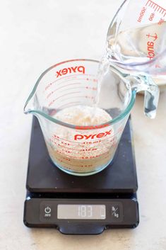 a measuring cup filled with flour sitting on top of a scale next to a bottle of water