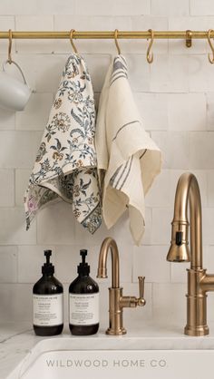 a kitchen sink with towels hanging on the rack above it and two hand soaps next to it