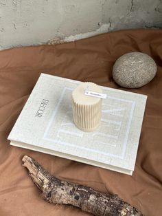 a white cup sitting on top of a book next to a rock