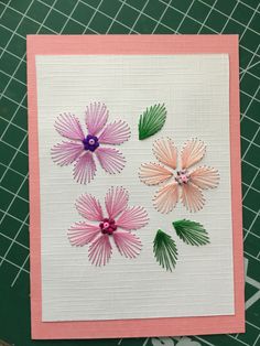 three pink and green flowers sitting on top of a piece of paper