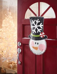 a red door with a snowman hanging from it's side and a candy cane in its mouth