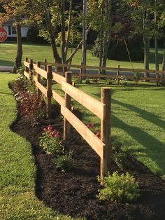 a wooden fence in the middle of a grassy field