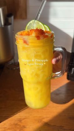 a person holding a mason jar filled with orange juice and topped with a slice of lime