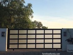 a white and black gate with trees in the backgroung area behind it