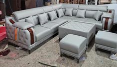 a grey leather sectional sofa and ottoman with matching footstools in a warehouse setting