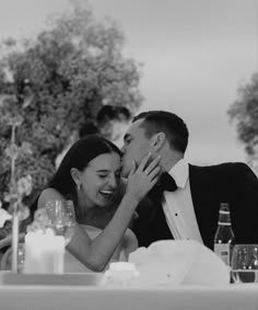 a bride and groom kissing in front of an outdoor dining table with candles on it