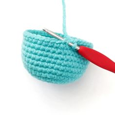 a crochet basket with a red handled handle and yarn ball attached to it