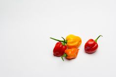 three red and yellow peppers on a white surface