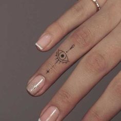 a woman's hand with a small tattoo on her left thumb and an eye in the middle